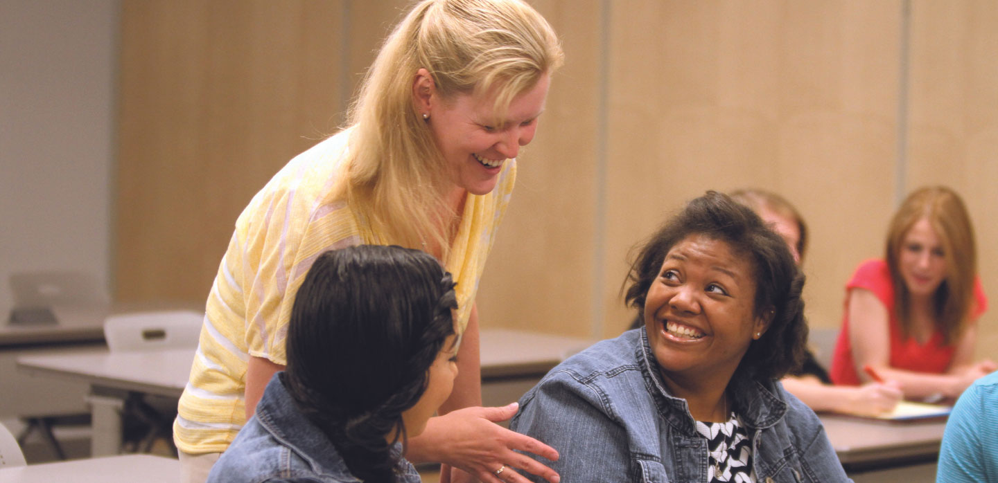 professor leaning over women talking