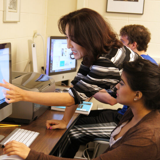 instructor pointing to student's computer screen