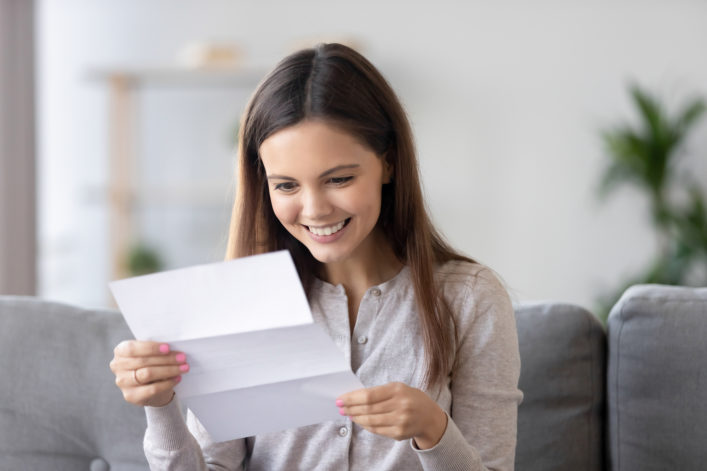 female smiling excitedly reading letter