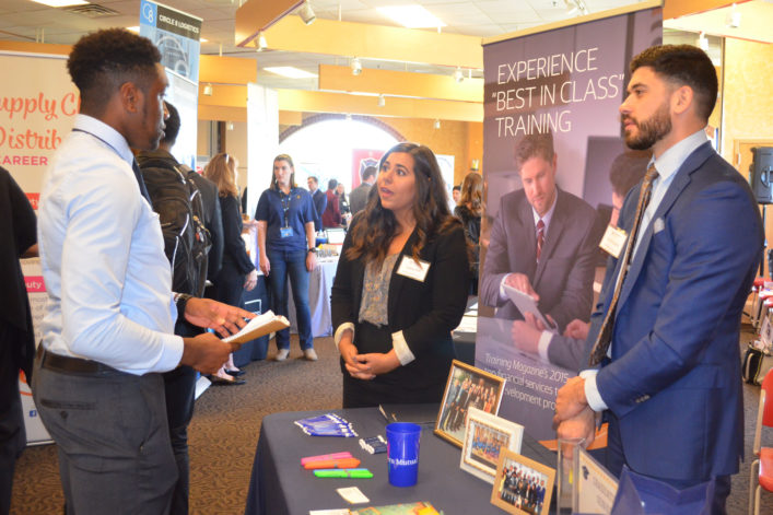 student speaking with company representatives at Career Fair