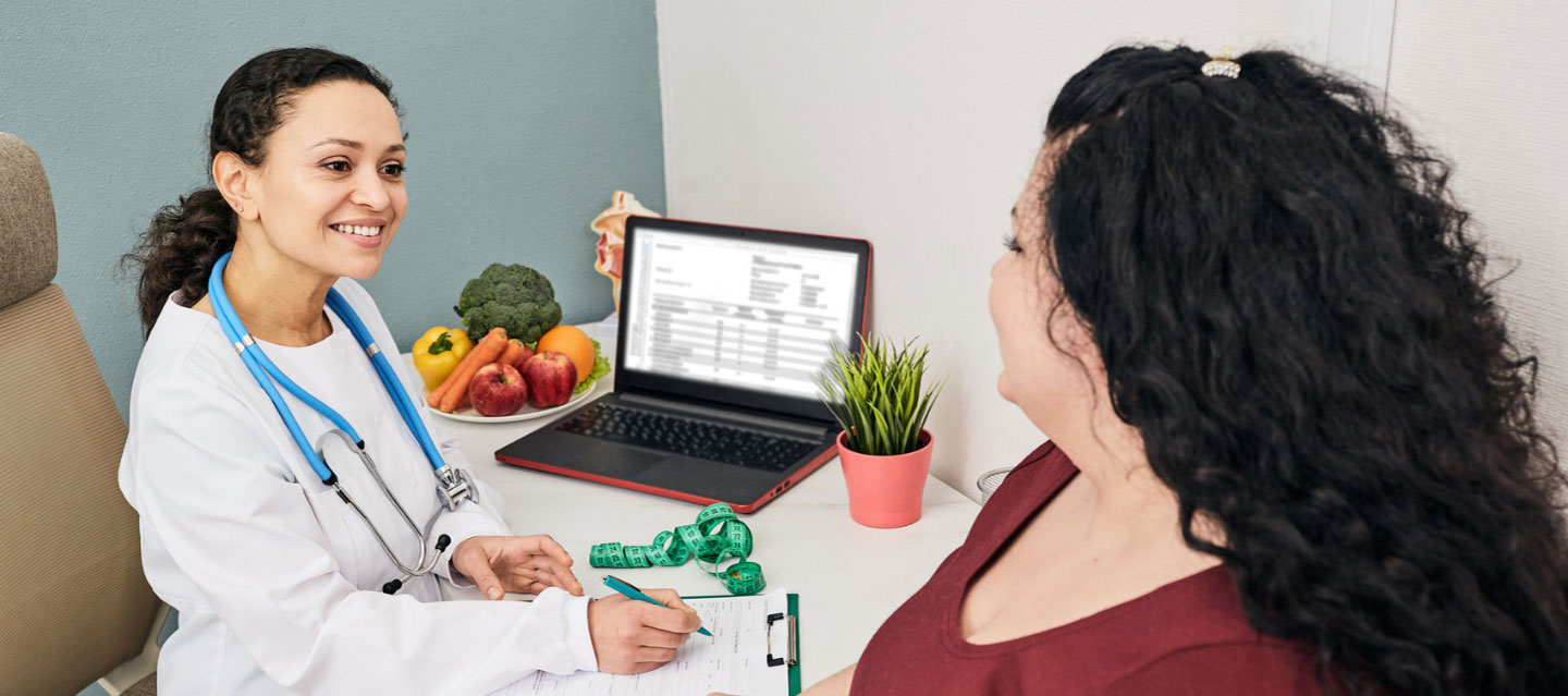 Dietician speaking with patient while sitting at desk with computer