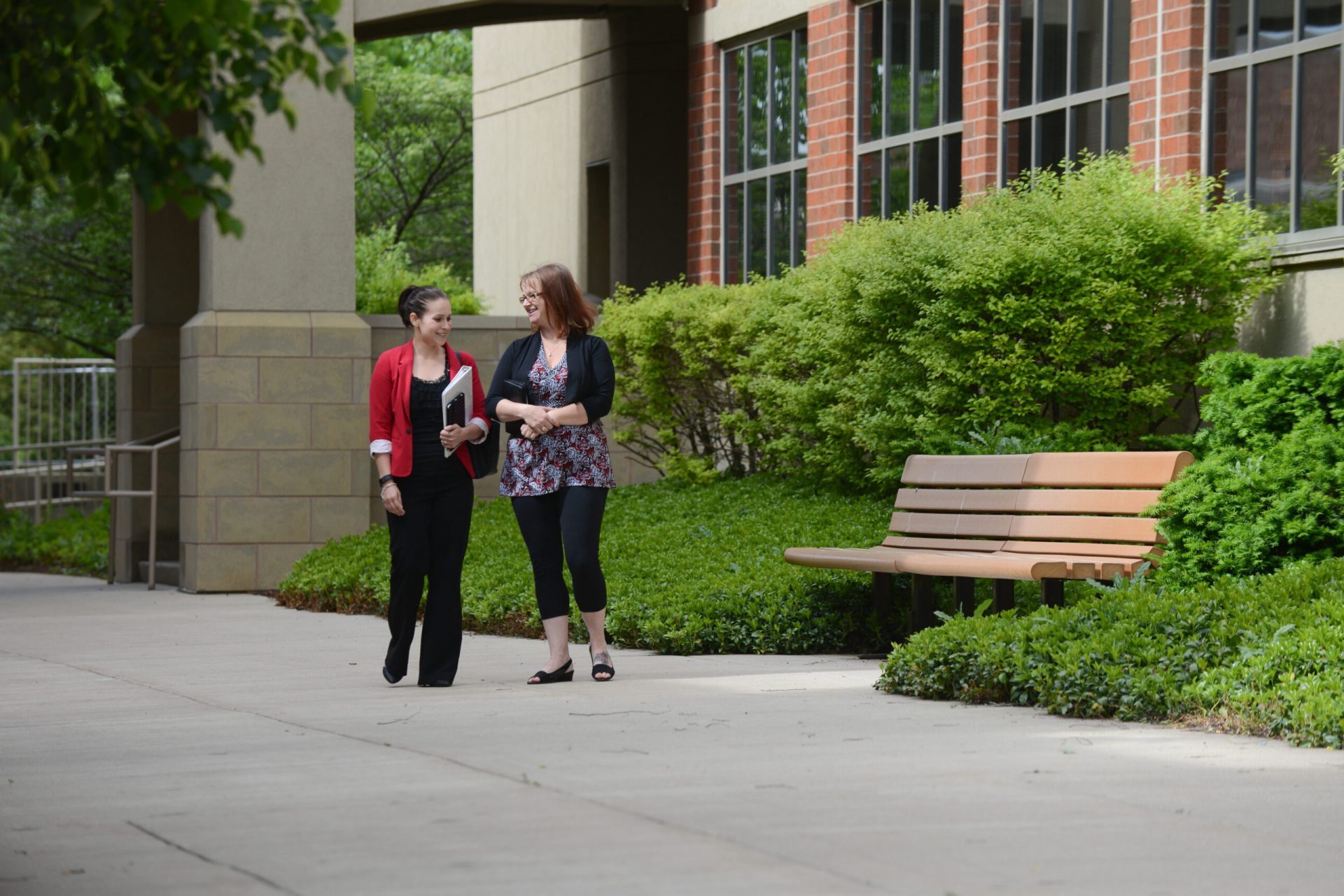 Two female, adult students, walking outside on campus