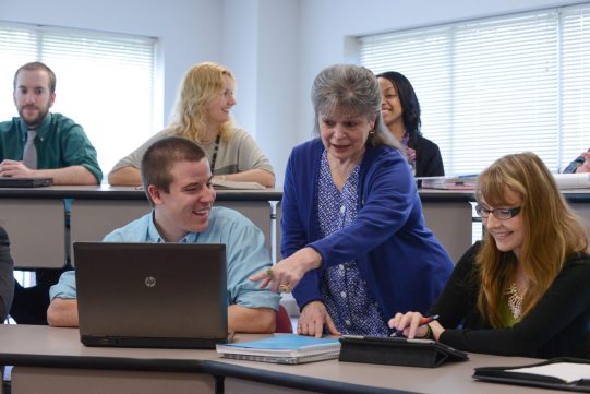 Adult students posed in lecture classroom, laptops, studying, learning, teaching