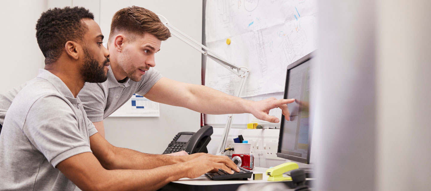 two male students working and pointing at the computer screen; engineering science