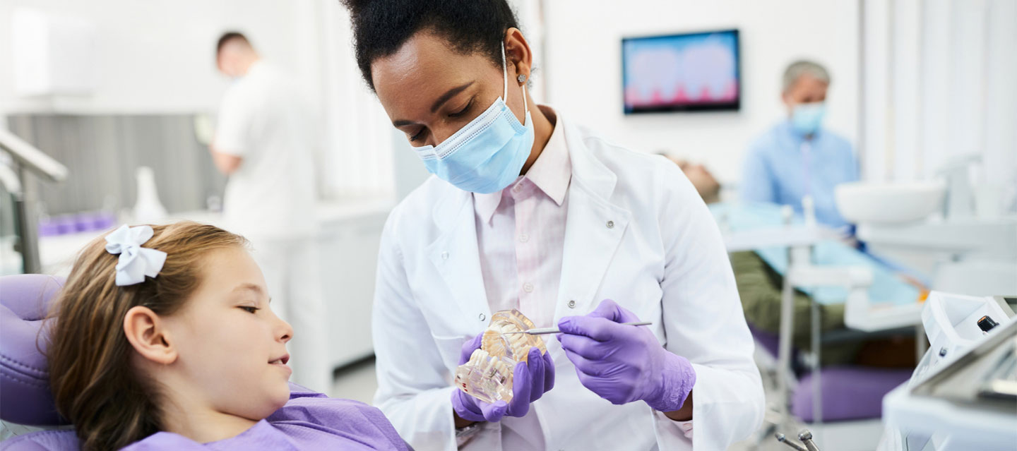 female dental student showing a child patient a model of teeth; pre-dentistry