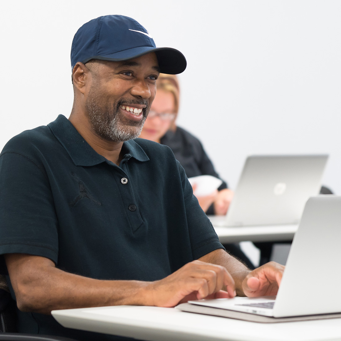 older male student smiling at laptop; financial aid for graduate and doctoral students
