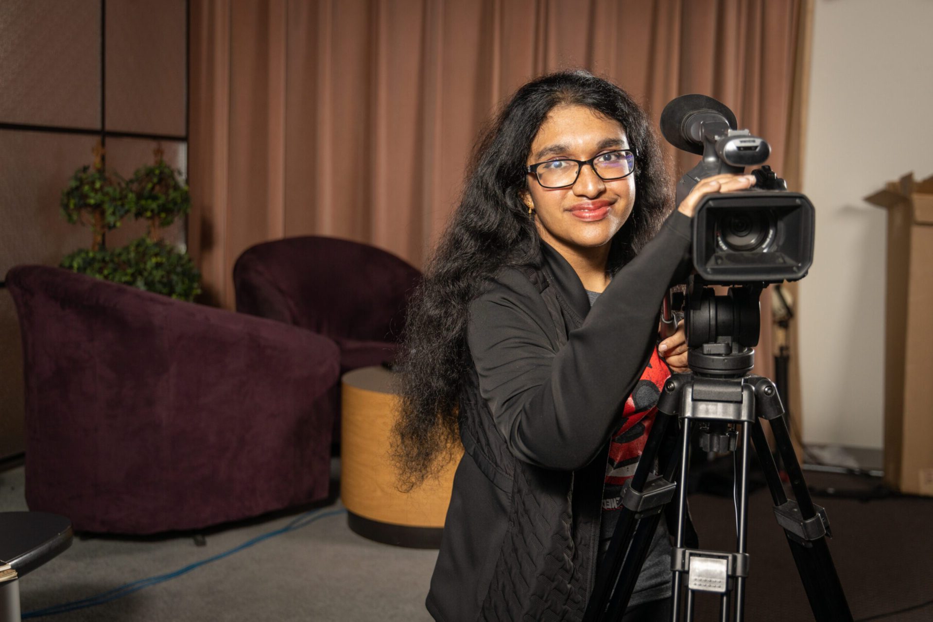 Female student operating a camera in the production studio, videography, communications, AV