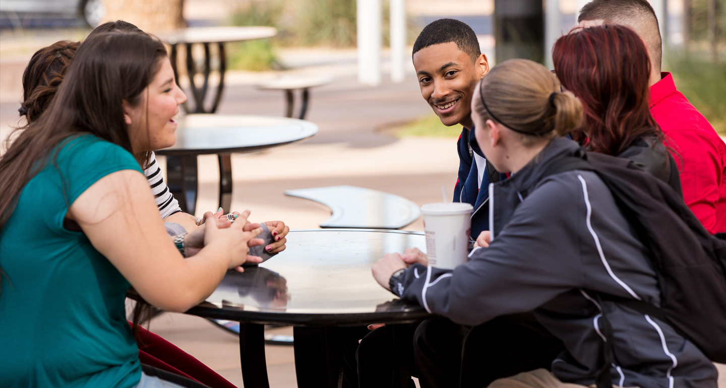 Group of transfer student talking at table outside