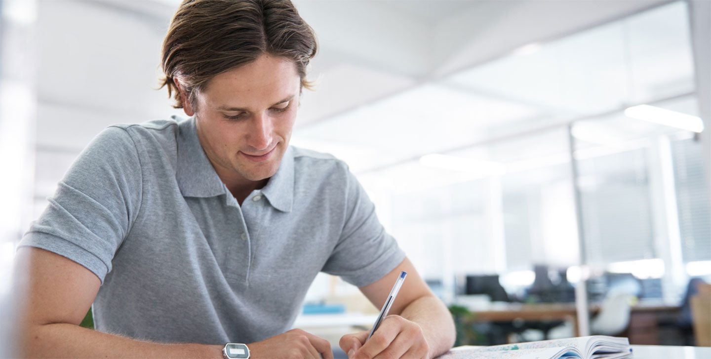 male student writing at desk; International Business and Economics program