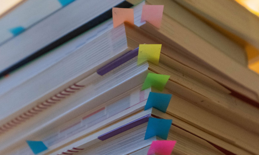 stack of books with colorful sticky tabs in each book; gender studies