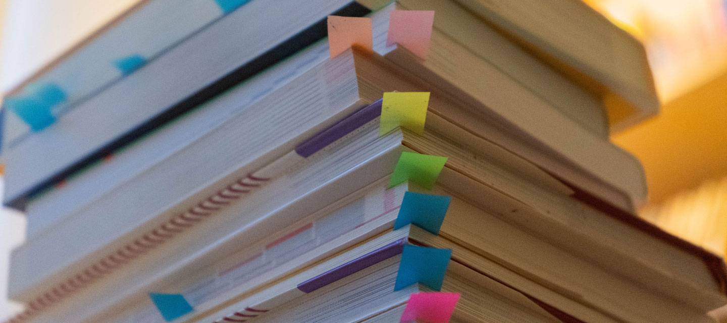 stack of books with colorful sticky tabs in each book; gender studies