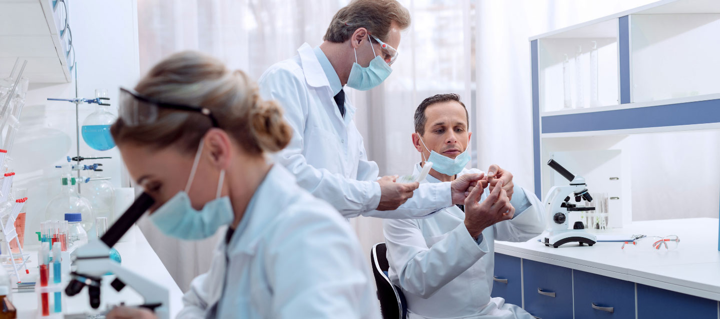 laboratory professionals in lab coats working in a lab examining specimens; chemistry