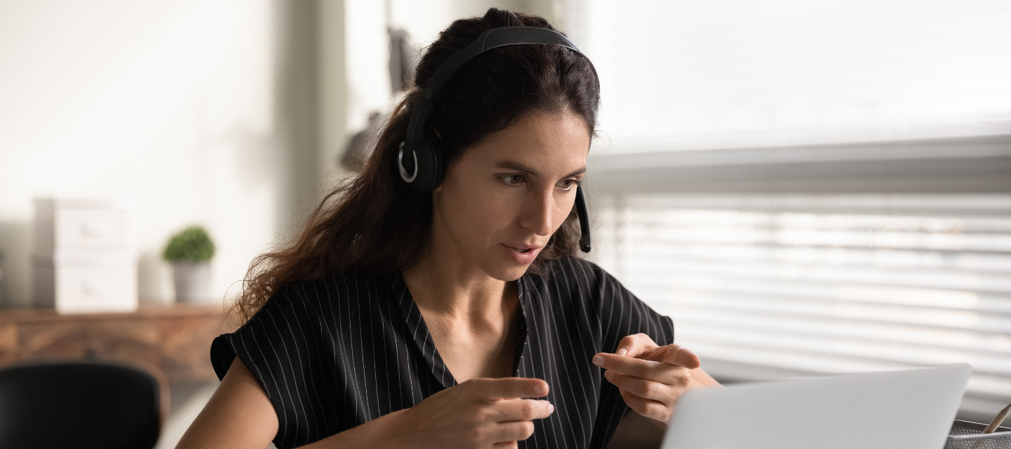 student with headphones studying her laptop screen; Spanish program