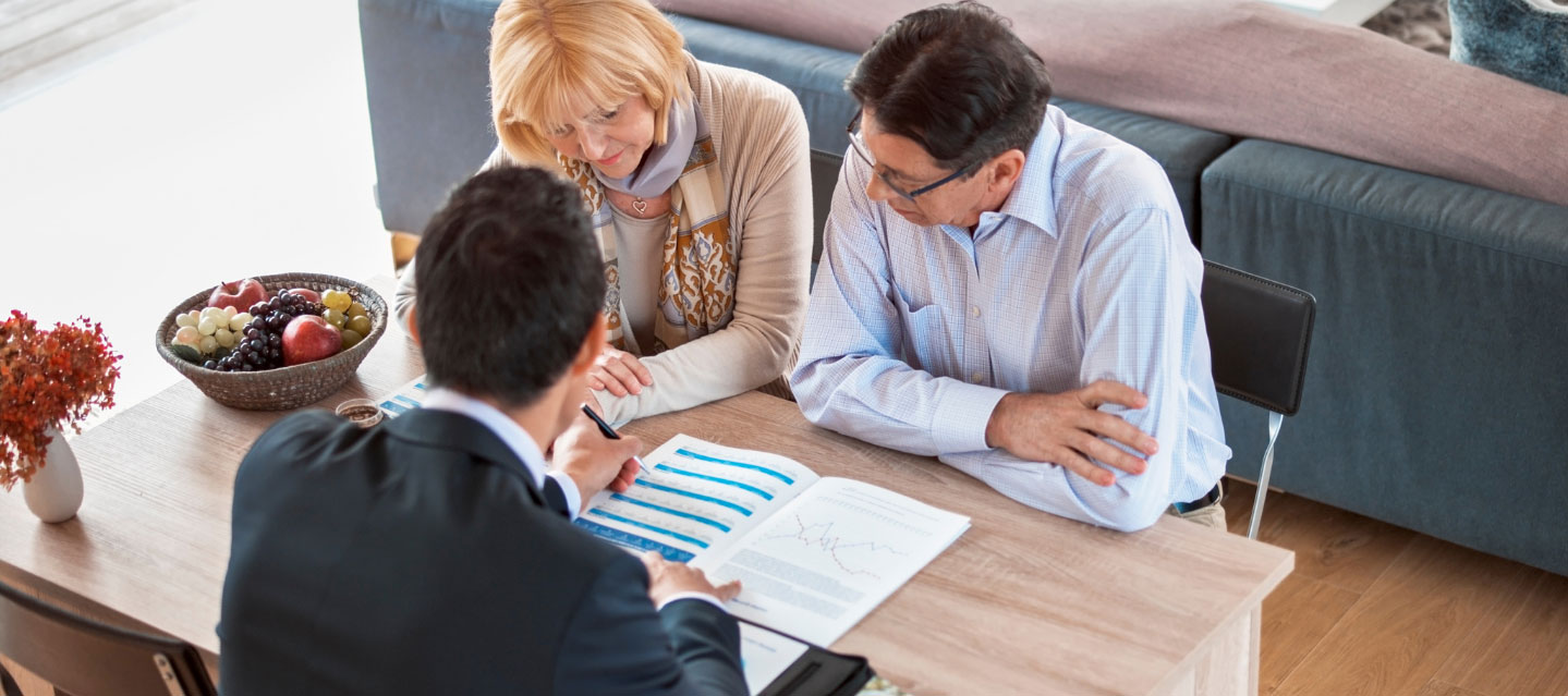 three business professionals meeting at a table looking at a chart in a notebook; business and economics