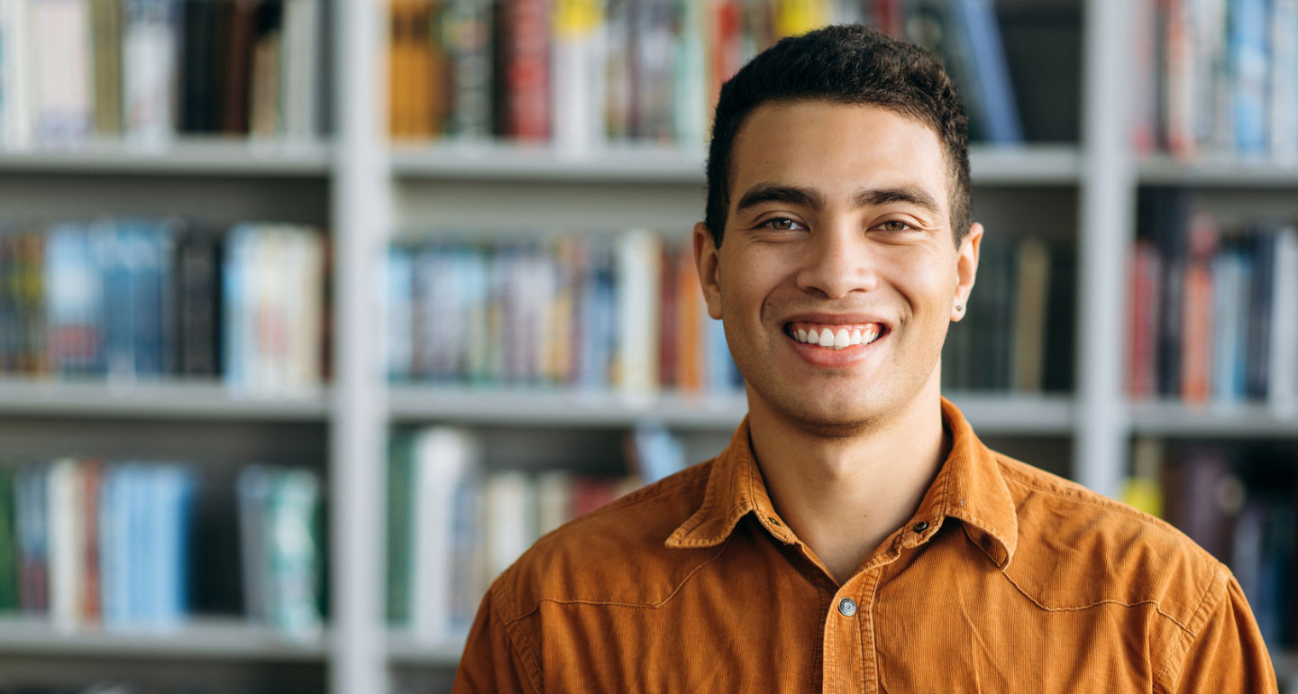 headshot of male Hispanic male smiling in front of book shelves; criminology program