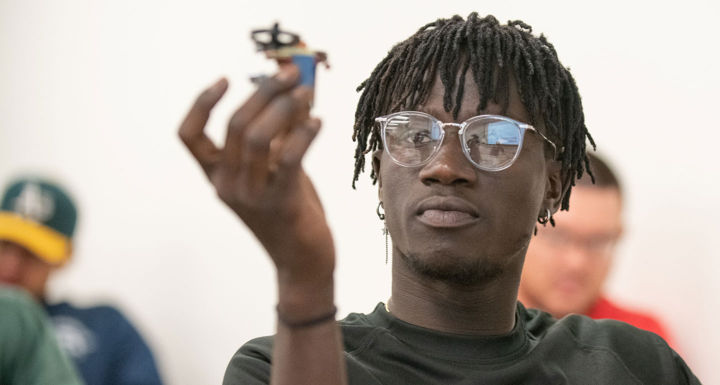 African American male student holding up gadget in engineering class; engineering science