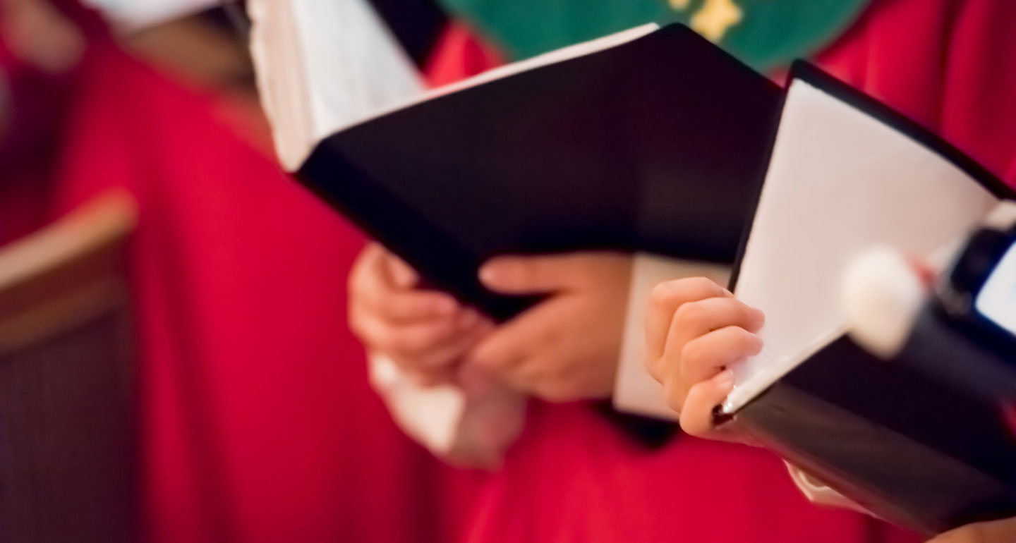 close up of hands holding music book; St. Benedict Chapel Choir