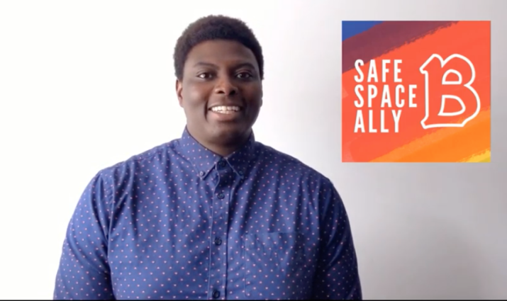 African American male standing by "Safe Space Ally" sign.