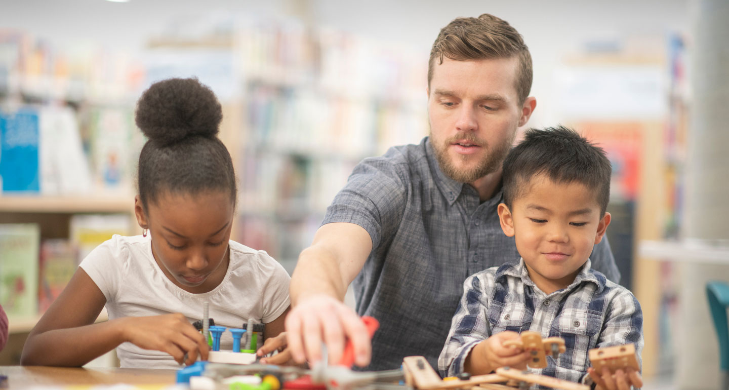 male teacher working with two elementary students; advising and licensure