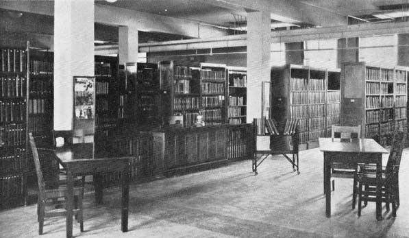 historic black and white photo of library book shelves and tables and chairs; archives