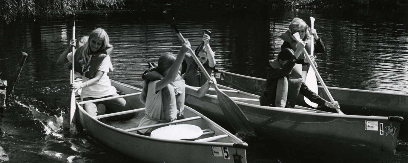 black and white photo of student paddling in canoes on Lake St. Benedict