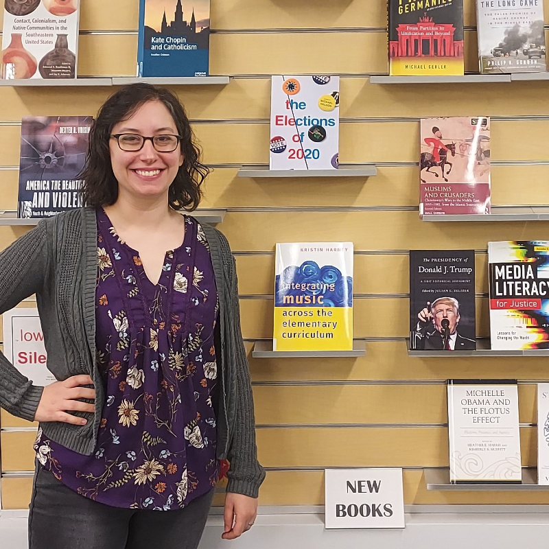 Joy Matteson, Benedictine University Librarian, standing in front of a wall of books
