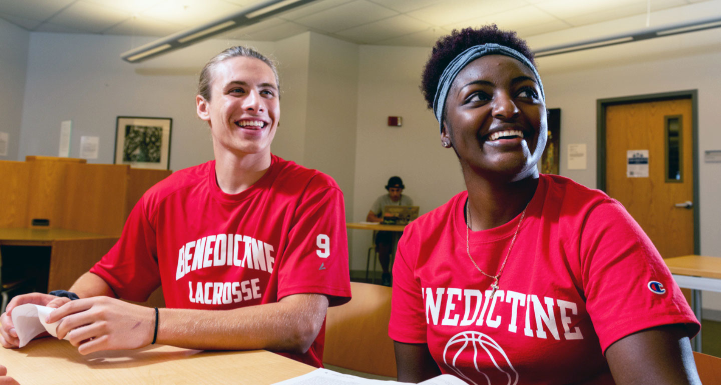 male and female Benedictine student athletes sitting in classroom smiling and look to right