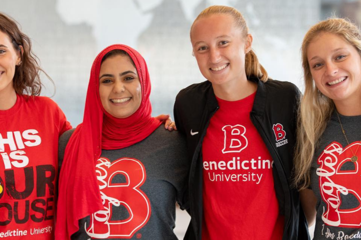 group of female student in Benedictine t-shirts posing in Goodwin smiling; scholars program