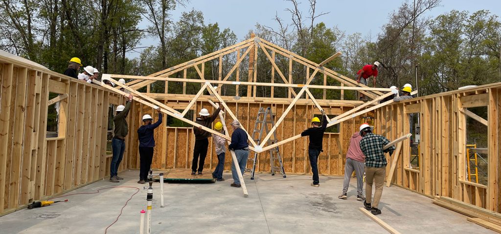 A group of people working on a house with wood framing.
