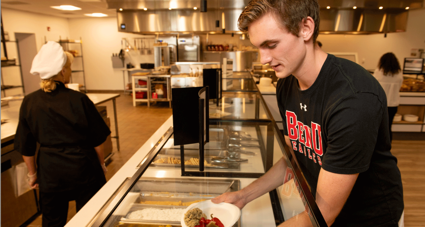 Meal plans. Male student loading his plate with food in Benny's