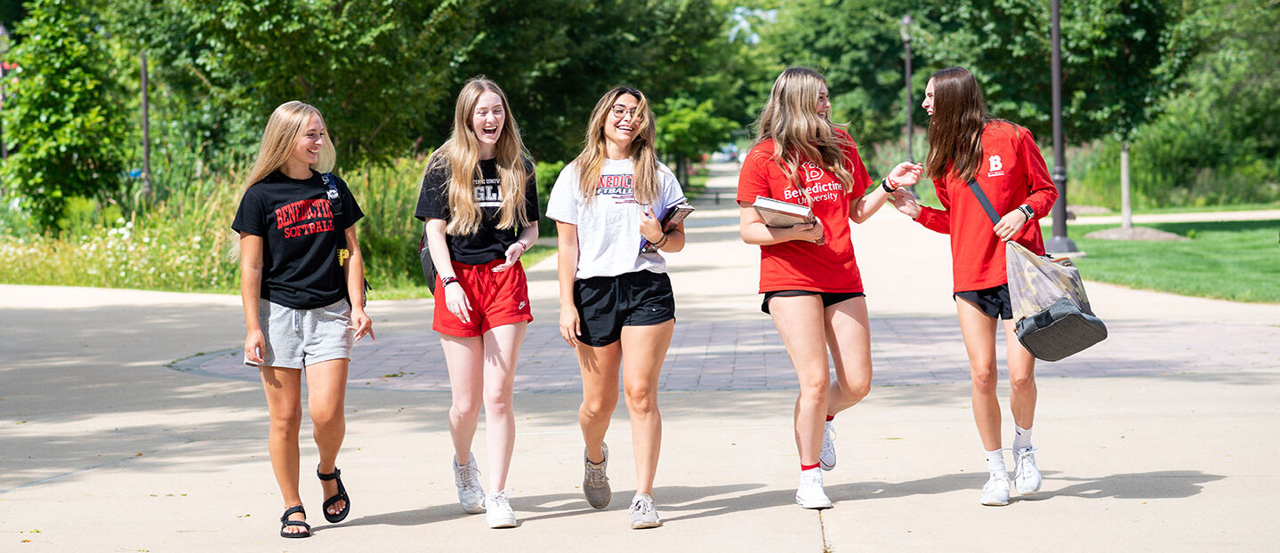group of female students walking on campus laughing