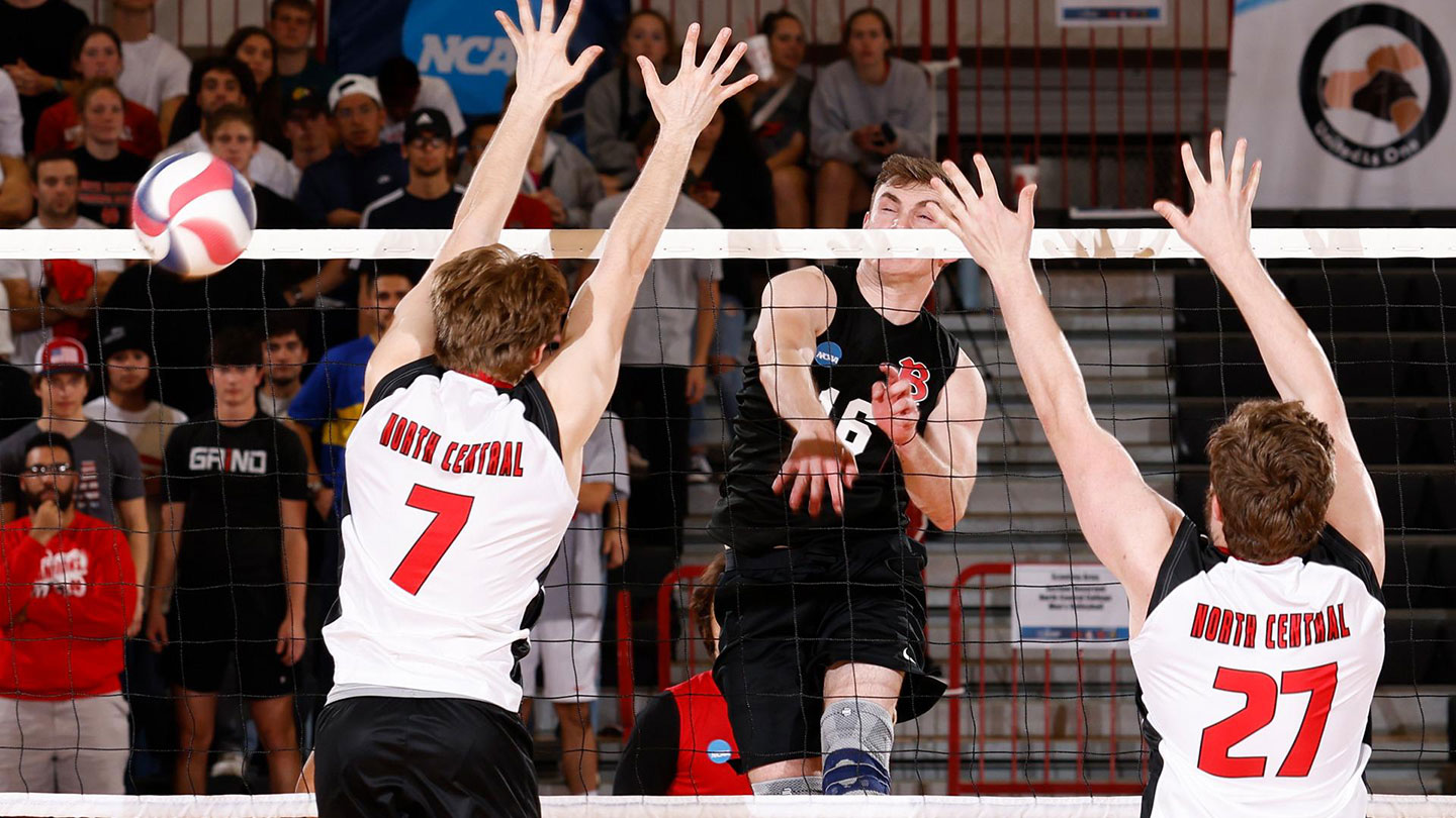 Men's Volleyball player spiking between opponents