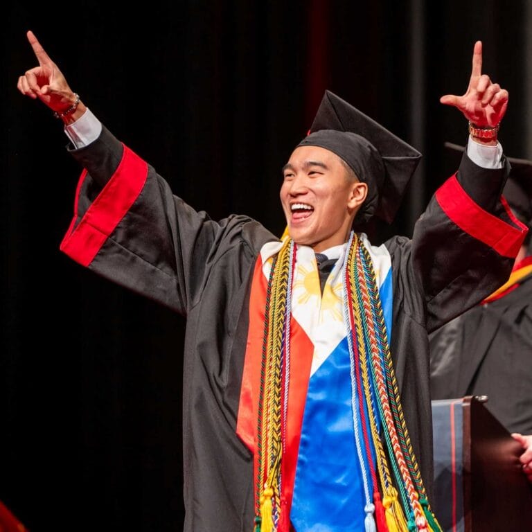 Picture of grad walking across the stage celebrating