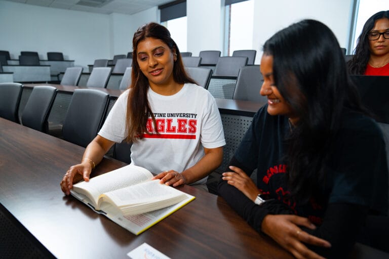 Two students reading a book in a classroom.