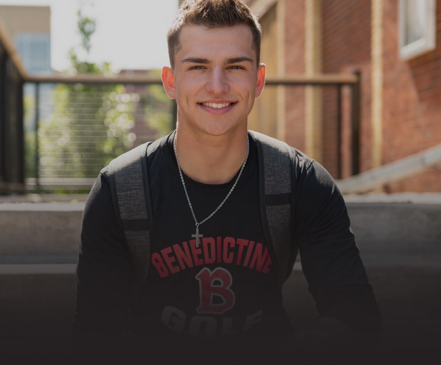 Male student smiling with backpack on steps of Coal Ben