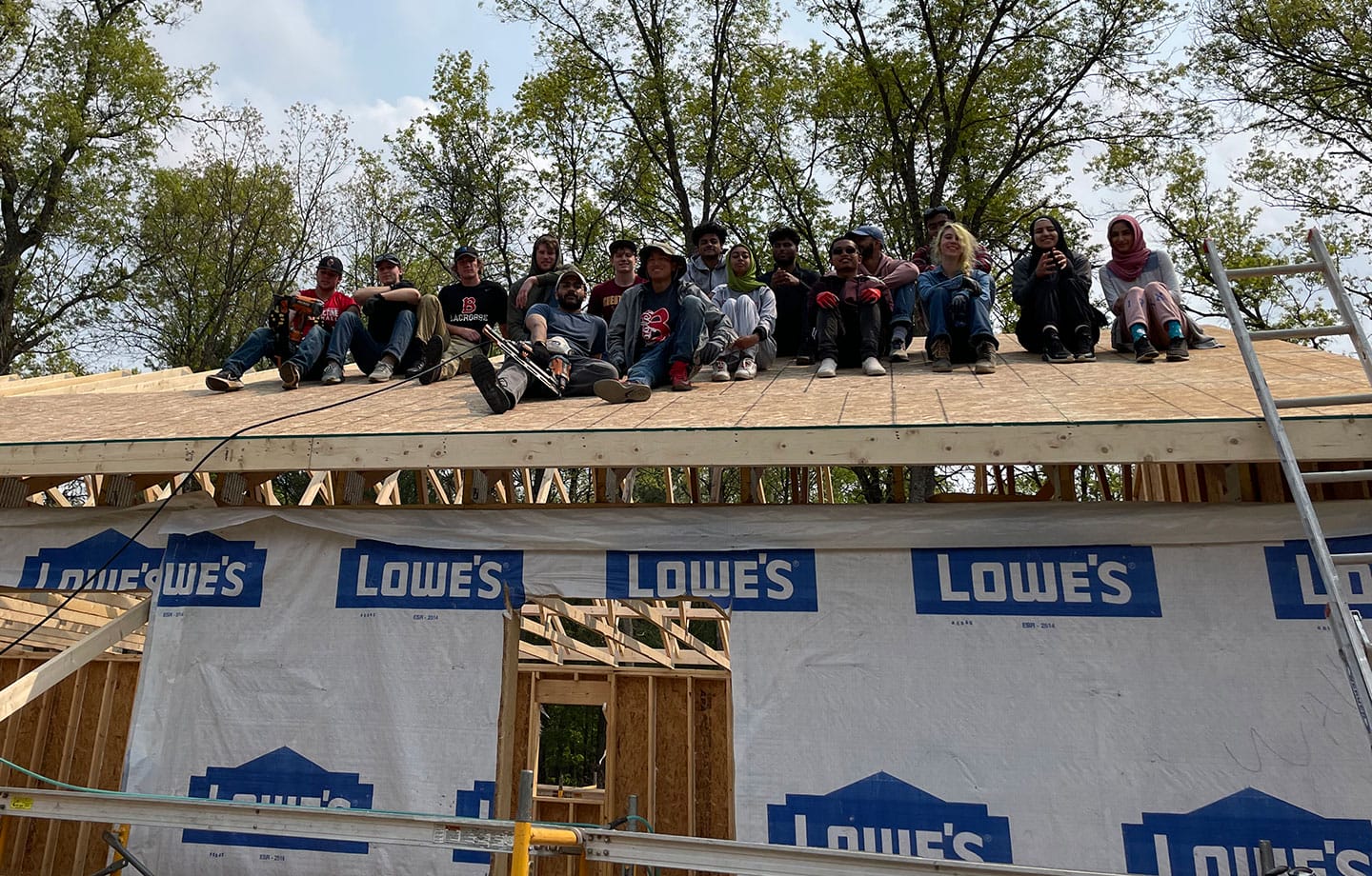 Scholars students sitting on roof of house being constructed in Baldwin MI